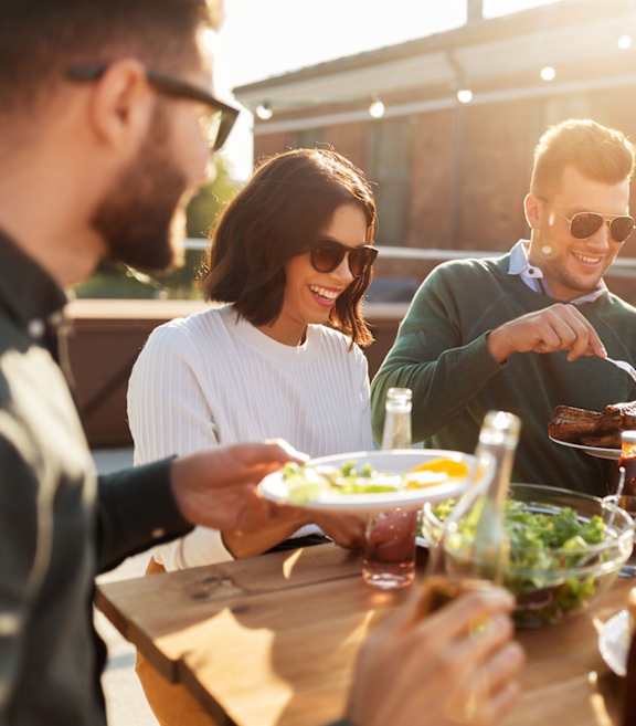 A group of people enjoying a meal together at an outdoor table.