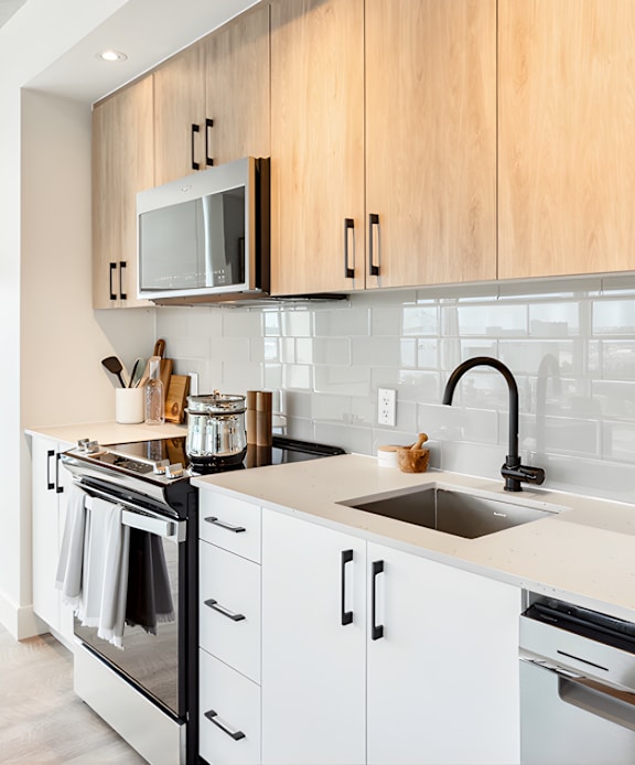 A modern kitchen with a stainless steel refrigerator and wooden flooring.