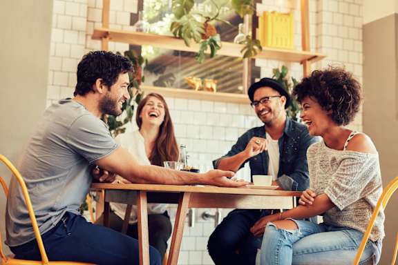 Four people are sitting around a table, laughing and enjoying each other's company.