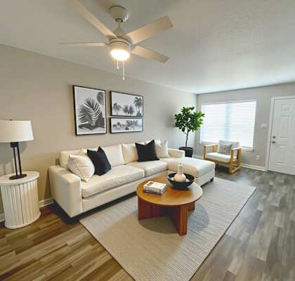 A living room with a white couch, a coffee table, and a ceiling fan.