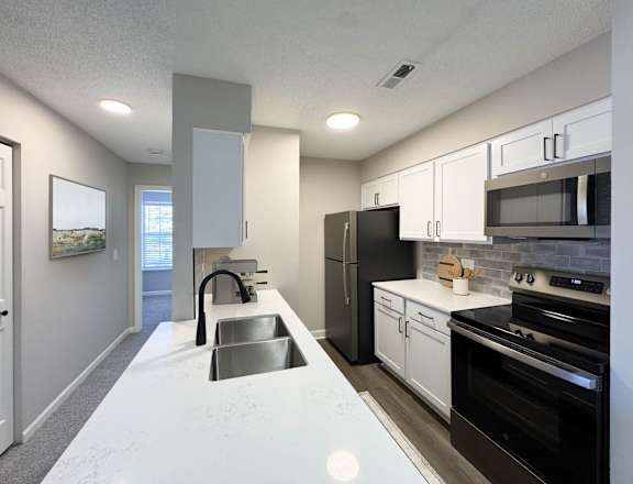 A modern kitchen with black appliances and white countertops.