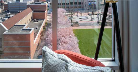 a view of the city from a hotel room with a couch and a lamp