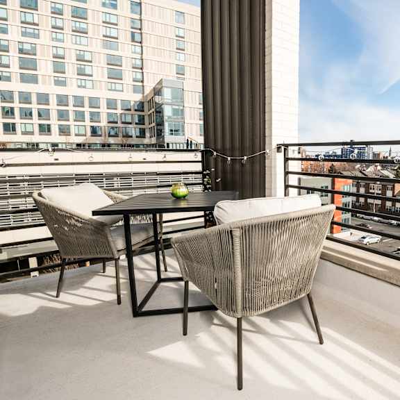 A balcony with a table and chairs overlooking a cityscape.