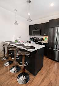 A kitchen with black cabinets and a white door.