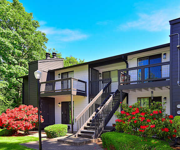 a building with a staircase and a yard with red flowers