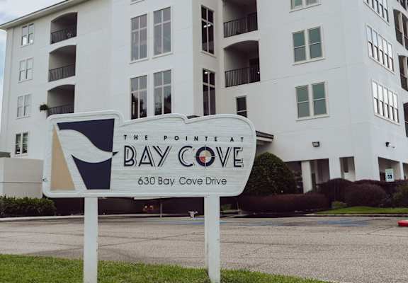 A white building with a sign that says Bay Cove in front of it.