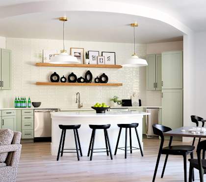 A kitchen with a white countertop and black bar stools.