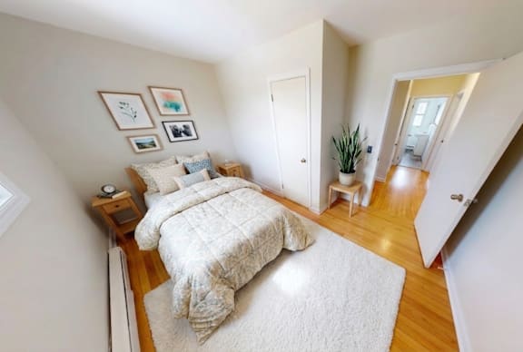 A bedroom with a bed, nightstand, and pictures on the wall.