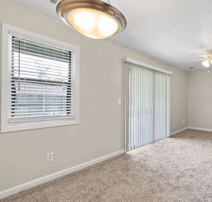 an empty living room with a window and a ceiling fan