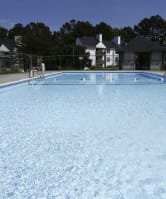 a large swimming pool with chairs and a fence around it
