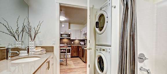 A modern bathroom with a washer and dryer built into the wall.
