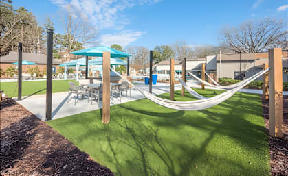 a playground with hammocks and tables and umbrellas