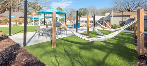 a playground with hammocks and tables and umbrellas