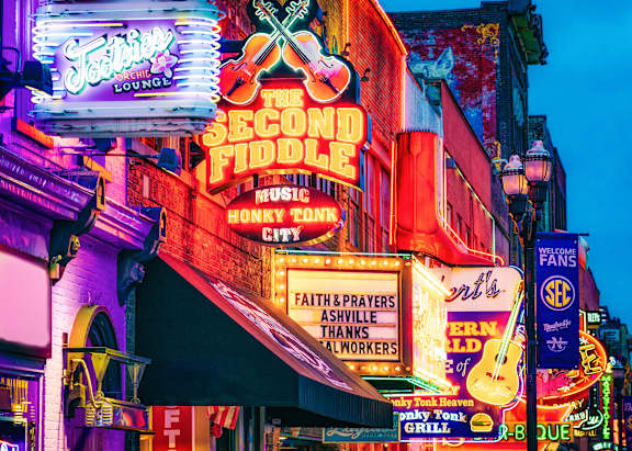 A brightly lit neon sign for The Second Fiddle Music Honky Tonk City.