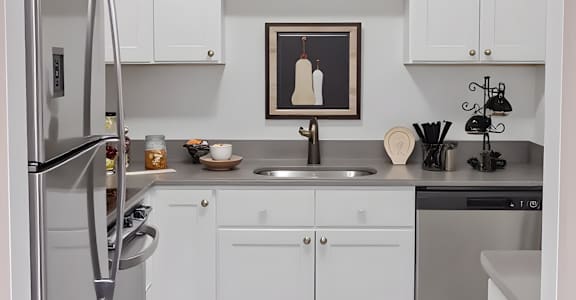 A modern kitchen with white cabinets and a stainless steel refrigerator.