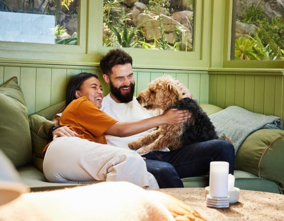 a man and woman sitting on a couch with a dog