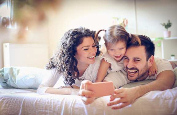 a family sitting on a couch in a living room looking at a tablet