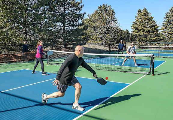 A man in a black shirt and gray shorts is playing tennis.