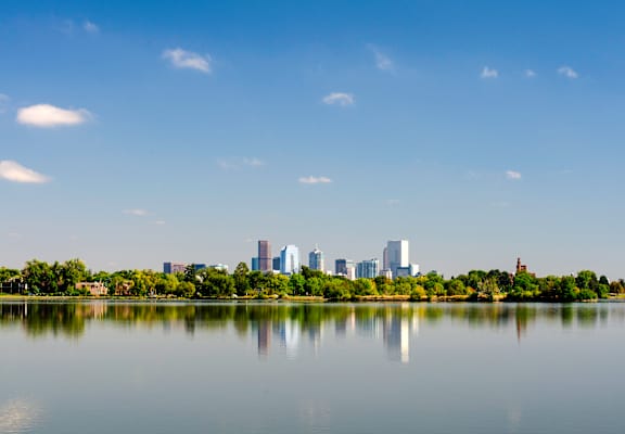 A city skyline is reflected in a body of water.