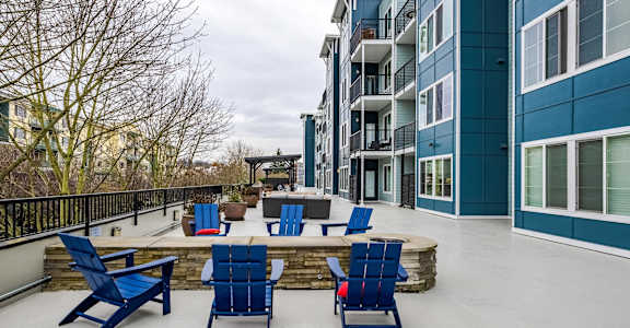 A patio with blue chairs and a table.