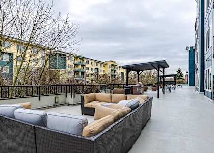 A rooftop patio with a black railing and a white couch.