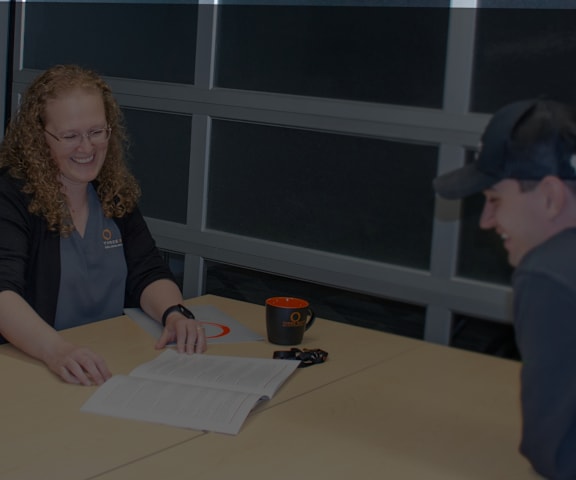 a woman sitting at a table signing a piece of paper