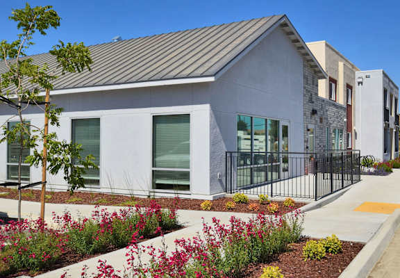 a building with a sidewalk and plants in front of it