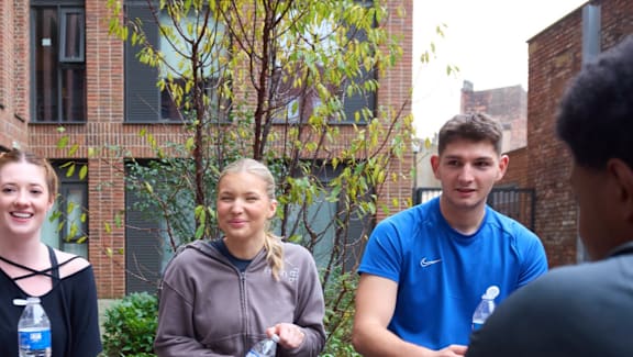 Four people standing outside talking to each other.