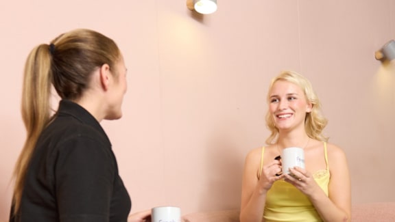 Two women having a conversation over coffee.