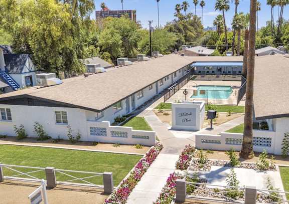 A white building with a pool in front of it.