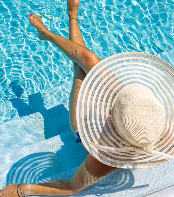 A woman in a straw hat is floating in a pool.