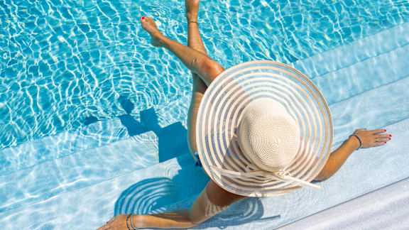 A swimming pool surrounded by a concrete patio and umbrellas.