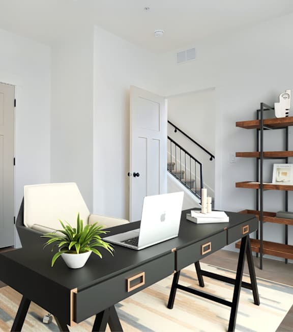 A black desk with a laptop and a plant on it.