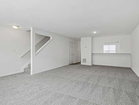 A spacious room with a staircase and a window.