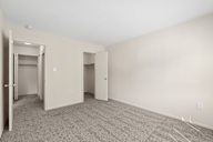 A room with a carpeted floor and two doors.