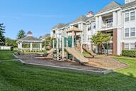 A playground with a slide and a gazebo in front of a building.