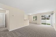 A large empty room with a carpeted floor and a window.