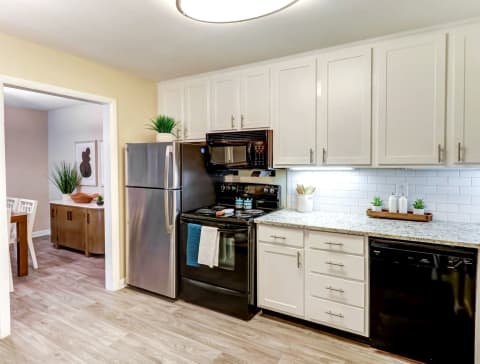a kitchen with white cabinets and black appliances