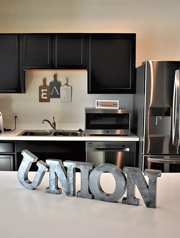 A kitchen with a stainless steel refrigerator and a countertop with the word at Union at Crescent, Bloomington, IN