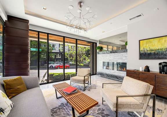 A modern living room with a grey sofa, wooden coffee table, and a large painting on the wall.
