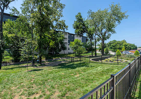 a grassy area with trees and a fence in front of a building