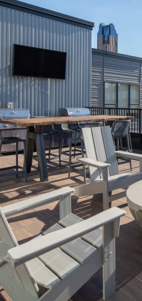 a roof deck with chairs and a fire pit and a city in the background