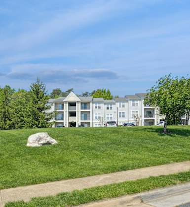 A grassy area with a building in the background and a lamp post on the left.