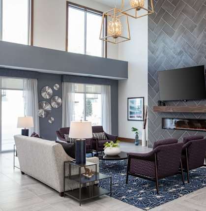 A modern living room with a grey sofa set and a fireplace.at The Edison at Spirit, Lakeville, MN 55044