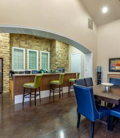 A kitchen with a stone wall and a dining table with blue chairs.