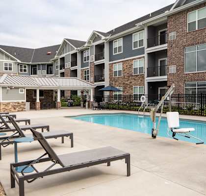 A pool area with sun loungers and a building in the background.