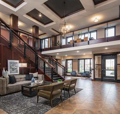 a lobby with a staircase and a living room with couches and chairs