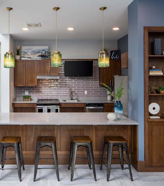 A kitchen with a bar area and a television mounted above the island.at The Edison at Spirit, Lakeville, MN