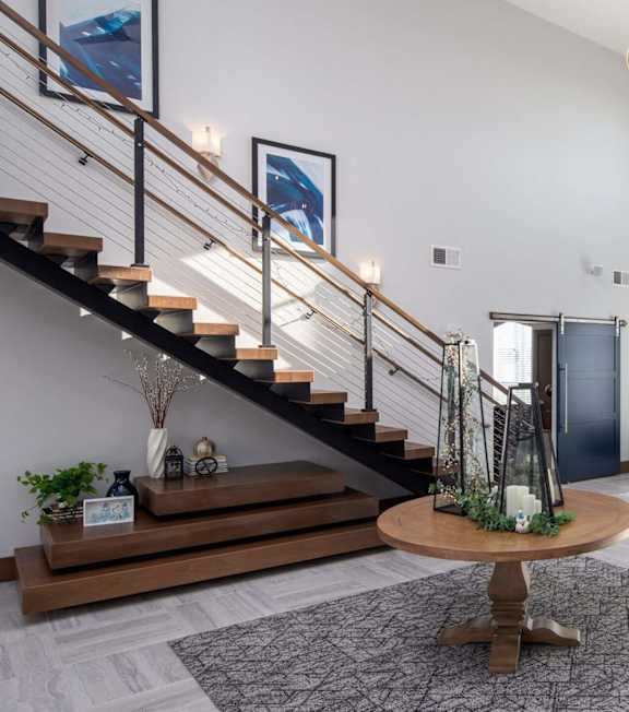 A living room with a staircase and a dining table.at The Edison at Spirit, Lakeville, MN