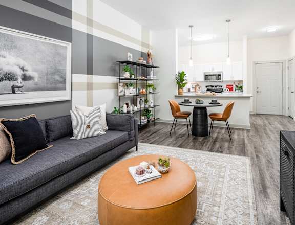 a living room with a couch a table and chairs and a kitchen in the background